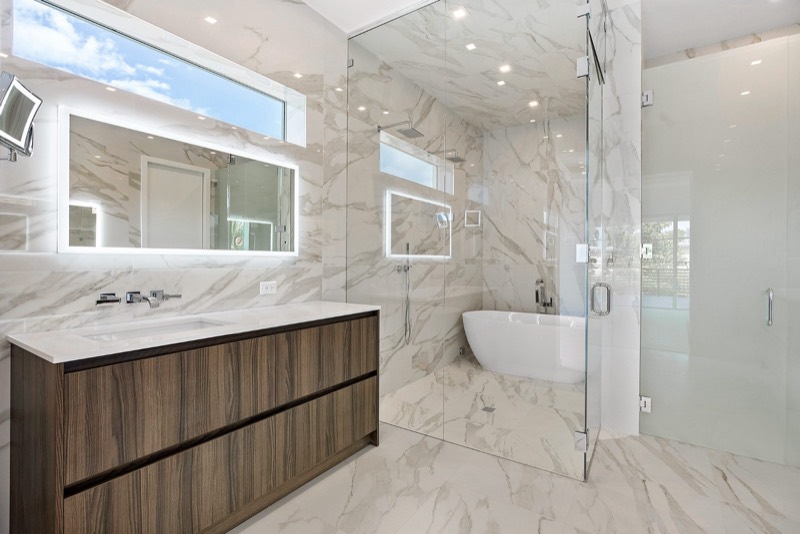 Contemporary master bath with backlit mirror and marble walls, Delray Beach FL